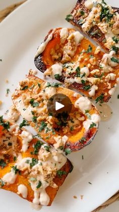 a white plate topped with three slices of stuffed sweet potatoes covered in cheese and herbs