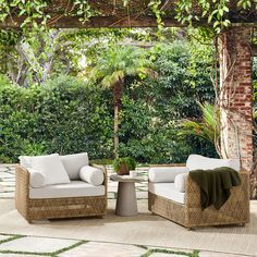 two wicker chairs sitting on top of a patio next to a table and potted plant