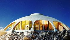 the dome shaped house is surrounded by rocks and boulders, under a night sky full of stars