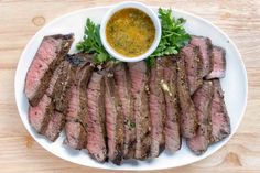 steak on a white plate with mustard and parsley garnished in small bowl