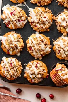 muffins with icing and cranberries on a baking tray