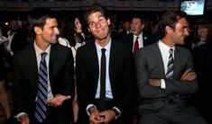 three men sitting next to each other in front of a group of people wearing suits and ties