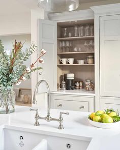 a bowl of fruit sitting on top of a kitchen counter next to a sink and cabinets