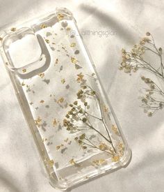 a clear case with flowers on it sitting on a white sheet next to a plant