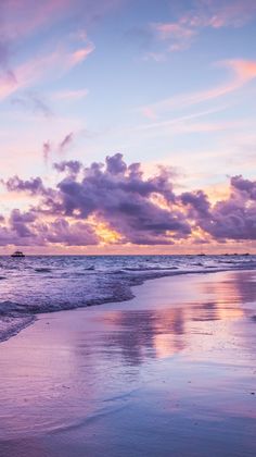 the sky is reflected in the wet sand on the beach as the sun goes down