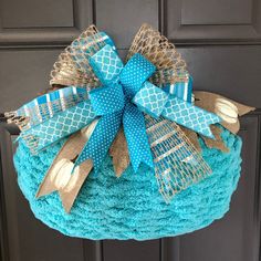 a blue crocheted basket with burlocks and bows hanging on the front door