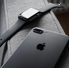 an apple watch sitting on top of a gray couch next to an iphone in front of it