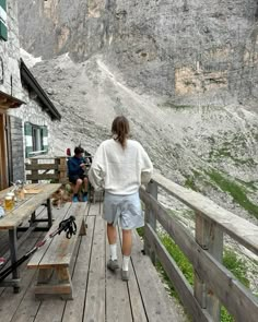 a woman standing on a wooden deck next to a mountain