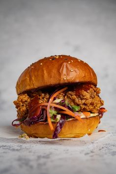 a fried chicken sandwich with lettuce and carrots