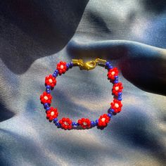 Red/Blue daisy chain bracelet with gold clasp. Red Flower-shaped Jewelry For Spring, Red Flower Jewelry For Spring, Red Flower-shaped Spring Jewelry, Red Flower Charm Jewelry For Spring, Red Jewelry With Flower Charm For Spring, Red Spring Jewelry With Flower Charm, Spring Red Jewelry With Flower Charm, Adjustable Vintage Bracelets For Summer, Handmade Red Bracelets For Spring