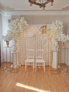 a room with white chairs and flowers on the wall, decorated with gold letters that spell out e