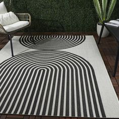 a black and white area rug in front of a chair with a plant on it