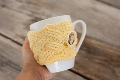 a hand holding a coffee cup with a yellow crochet pattern