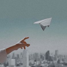 a person is flying a paper airplane in the sky