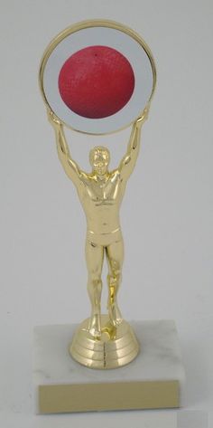 a gold trophy with a red ball in the center and a man holding it up