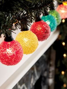 christmas lights hanging from the top of a tree in front of a decorated fireplace mantel