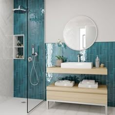 a bathroom with blue tiles and white fixtures, including a shower head mounted on the wall