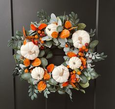 a wreath with white pumpkins and greenery