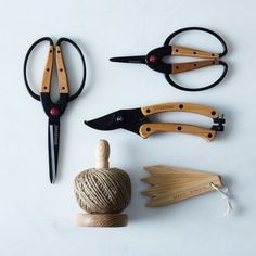 three pairs of scissors are sitting next to a ball of twine and a pair of pliers