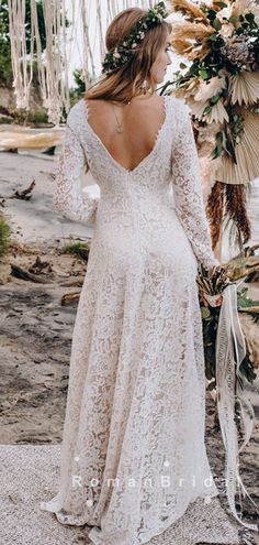 a woman wearing a white dress standing in front of an arch with flowers on it