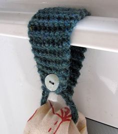 a crocheted hat hanging from the side of a door handle with a button on it