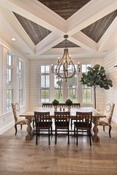 a dining room table with chairs and a chandelier hanging from the vaulted ceiling