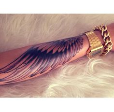 the arm is covered in gold chains and wings, with an eagle tattoo on it