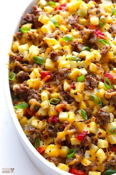 a casserole dish with meat, cheese and green onions in a white bowl