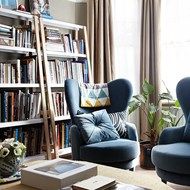 a living room filled with furniture and a book shelf next to a window covered in books