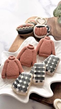 some cookies are sitting on a plate with plaid sweaters and mittens in the middle