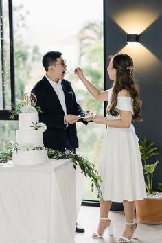 a bride and groom feeding each other cake at their wedding reception in front of a large window