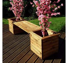 two wooden planters with pink flowers in them on a decking area near grass