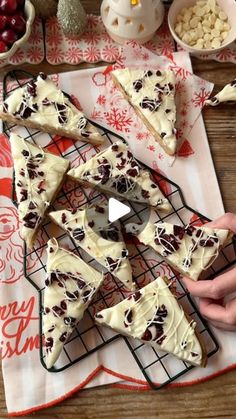 someone is cutting up some christmas cookies on a table with other holiday treats around them