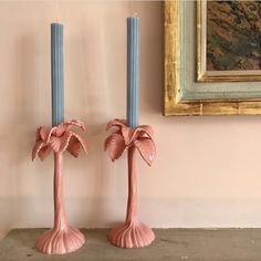 two pink vases sitting next to each other with blue candles in front of them