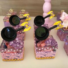 two small boxes with black lids on top of a table next to pink and yellow decorations