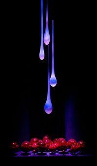 three drops of water hanging from the ceiling in front of some red and blue balls