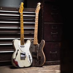 two guitars sitting next to each other on the floor