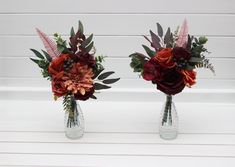 two vases filled with flowers on top of a white table next to each other