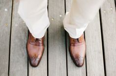 a man in white pants and brown shoes is standing on a wooden platform with his feet up