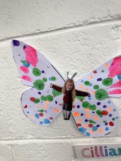 a child's paper butterfly hanging on the wall in front of a sign that reads,