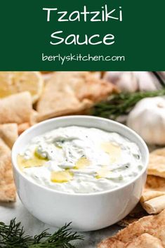 a white bowl filled with tzatzki sauce surrounded by tortilla chips