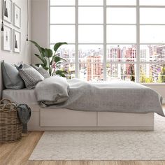 a white bed sitting in a bedroom on top of a hard wood floor next to a window