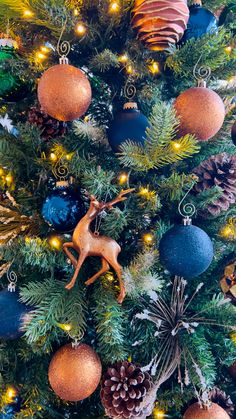 a christmas tree with blue and gold ornaments on it's branches, including a deer ornament