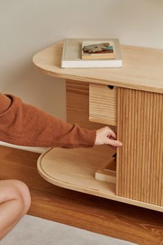 a woman sitting on the floor pointing at a book shelf