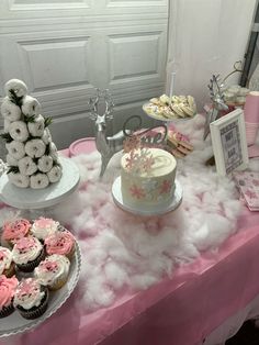 a table topped with cakes and cupcakes on top of a pink table cloth