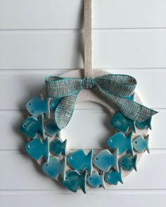 a wreath made out of ceramic fish hanging on a wall with a ribbon around it