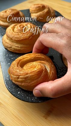 a person is picking up some cinnamon - sugar croissants on a black plate