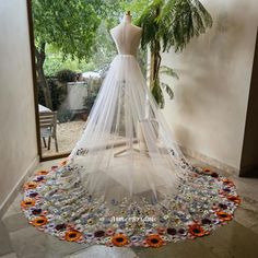 a wedding dress on display in front of a window with flowers and leaves around it