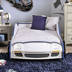 a child's bedroom decorated in blue and white with sports cars on the wall