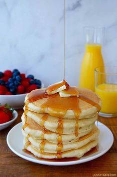 a stack of pancakes on a plate with syrup being drizzled over them